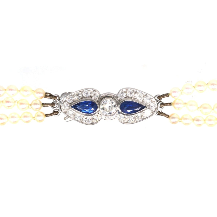 1940s triple strand cultured pearl necklace with sapphire and diamond clasp, featuring creamy white pearls and royal blue sapphires.