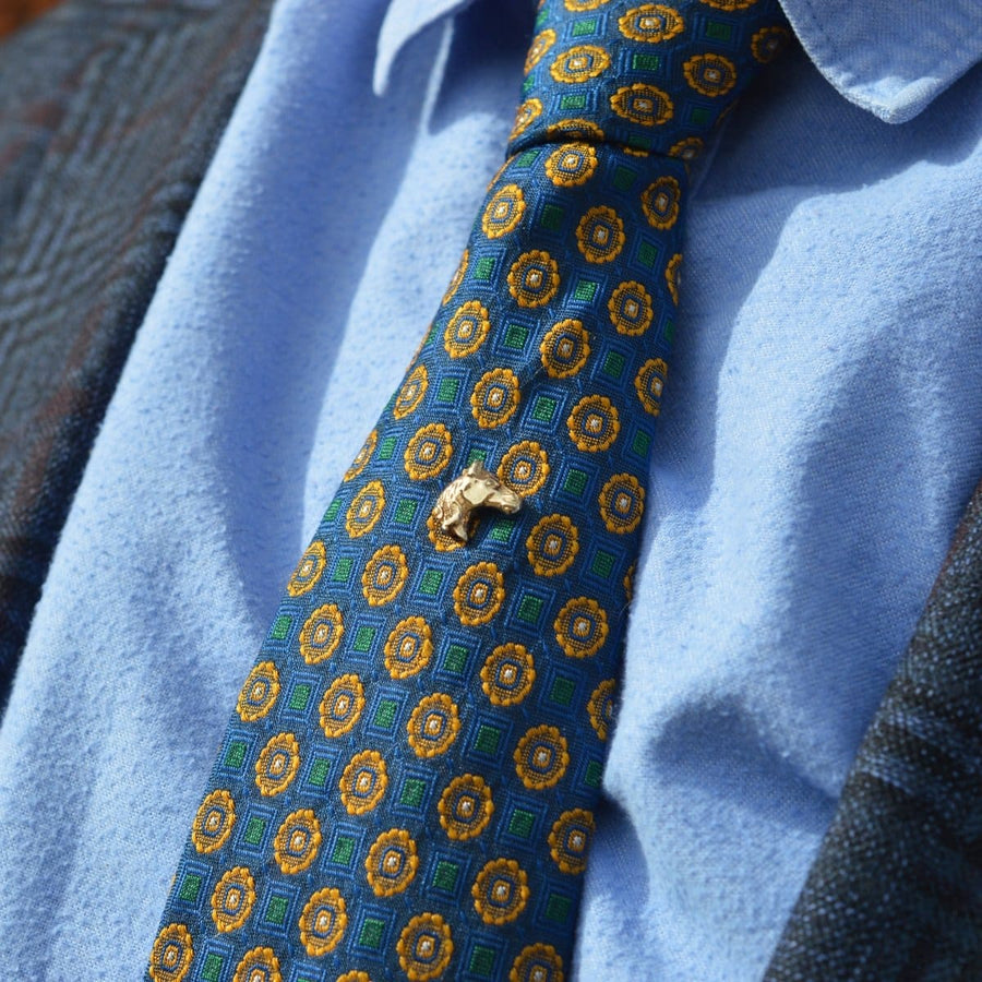Vintage 1950s 9ct gold horse head tie pin on a patterned tie, perfect accessory for horse racing events.