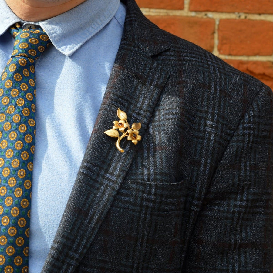 1960s 9ct gold and garnet floral spray brooch worn on a jacket, showcasing elegant jewelry design.