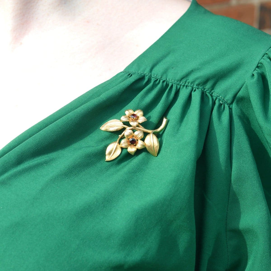 9ct gold and garnet floral spray brooch worn on green dress, showcasing vintage elegance and craftsmanship from the 1960s.