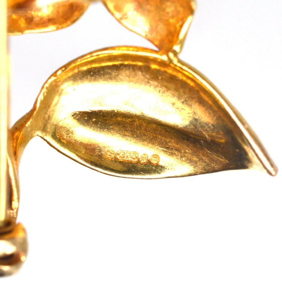 Close-up of a 1960s gold brooch detail showing intricate leaf design and hallmark.