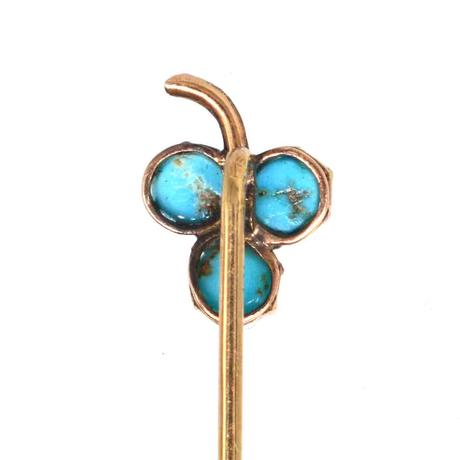 Close-up of Edwardian 9ct gold shamrock tie pin with turquoise beads and pearl at center, symbolizing good luck.