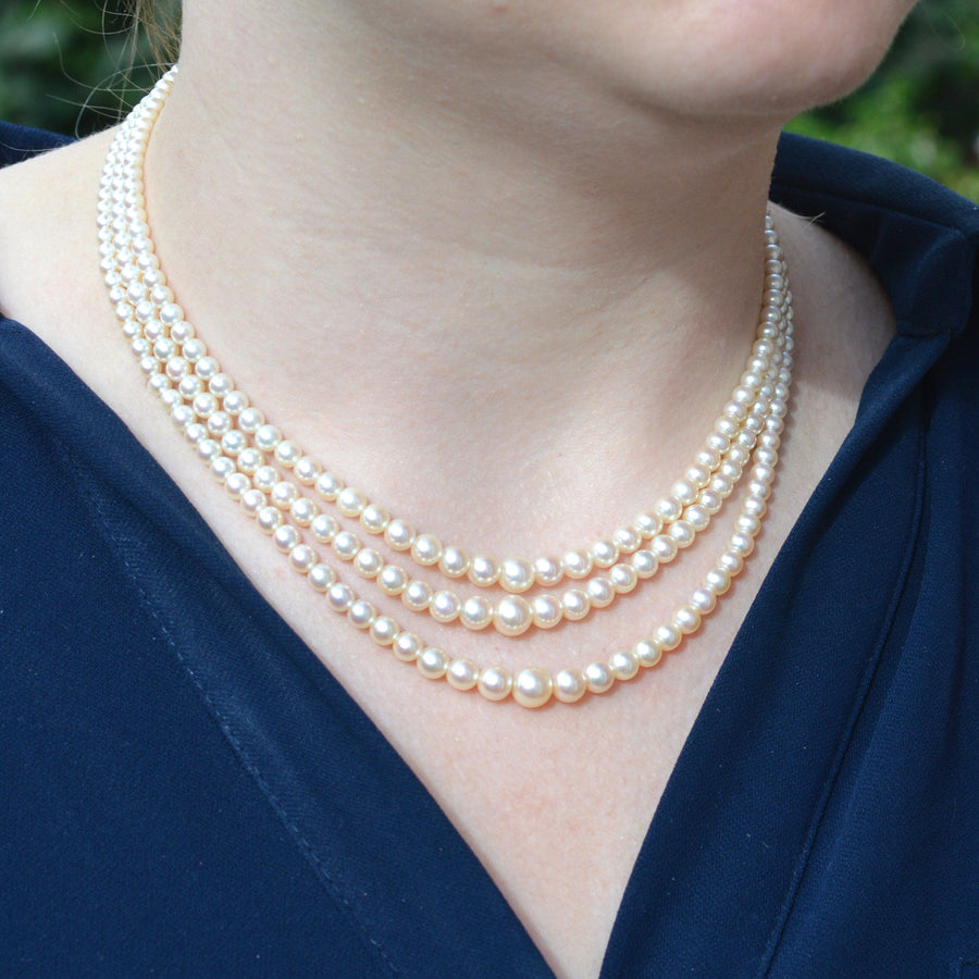 Triple strand cultured pearl necklace showcasing creamy pearls worn elegantly.