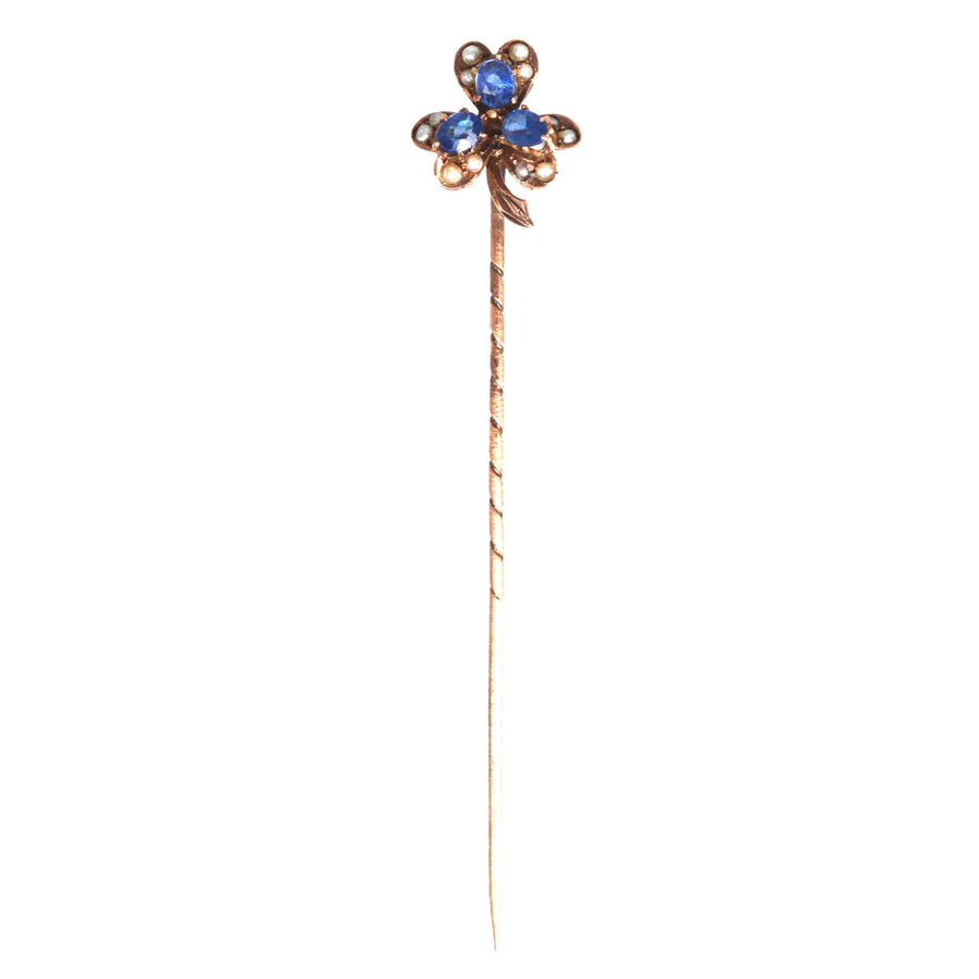 Early 20th century 8ct gold tie pin featuring a three-leaf clover design with blue sapphires and seed pearls.