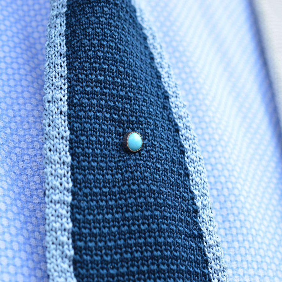 Edwardian 9ct gold turquoise tie pin accentuating a stylish silk tie, showcasing vibrant turquoise in millegrain setting.