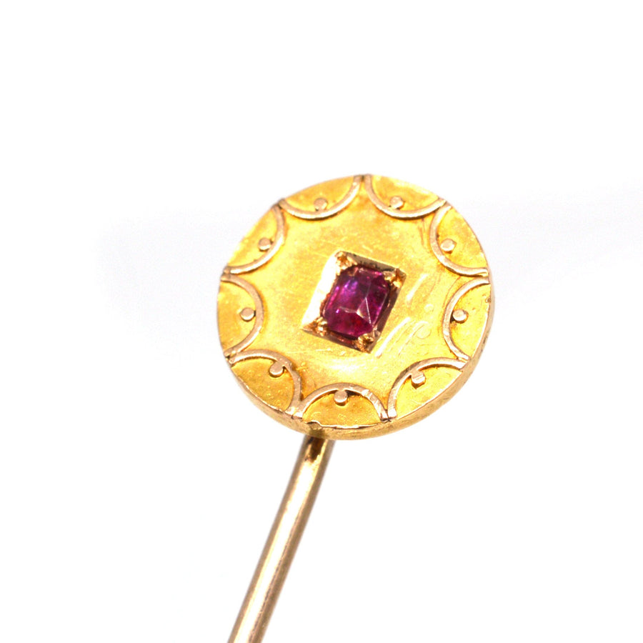 Victorian 15ct gold circle tie pin featuring a natural ruby, showcasing intricate gold swirls, from the 1880s.
