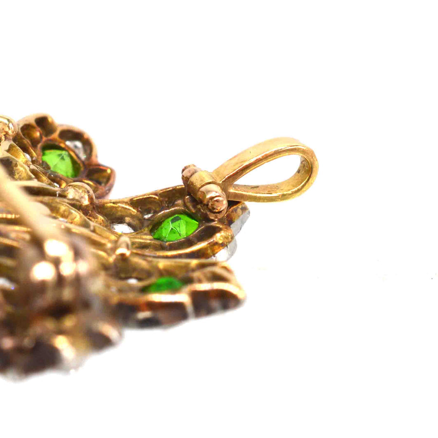 Close-up of a vintage gold peacock brooch with green demantoid garnets, showcasing intricate details.