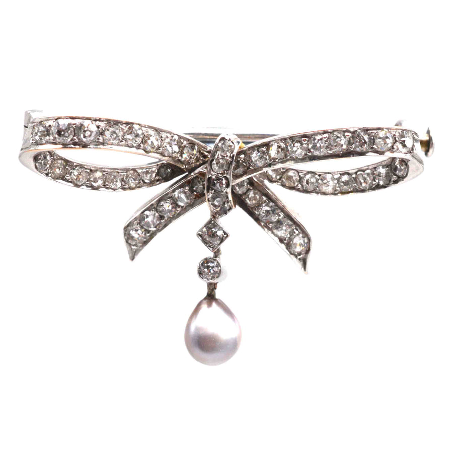 Early 20th century bow brooch in 14ct white gold with diamonds and a grey pearl drop.