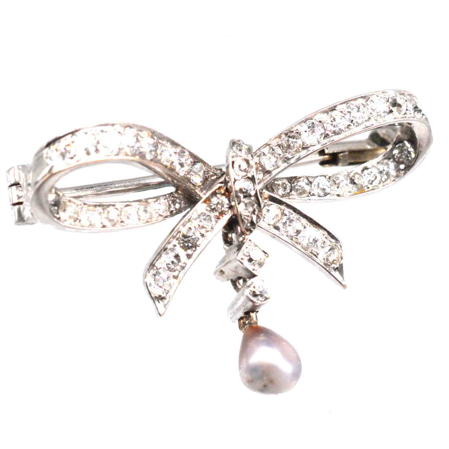 Early 20th century 14ct white gold brooch featuring diamonds and a grey pearl in a bow design.
