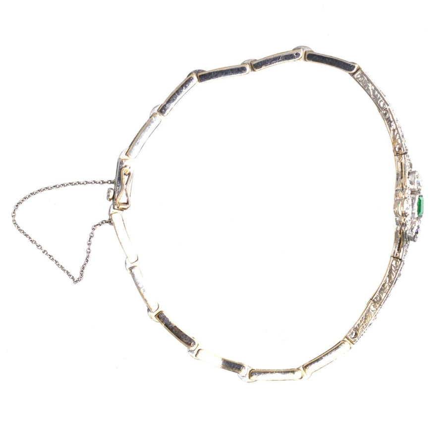 Art Deco white gold bracelet featuring square-cut emerald and two old European cut diamonds, secured with safety chain.