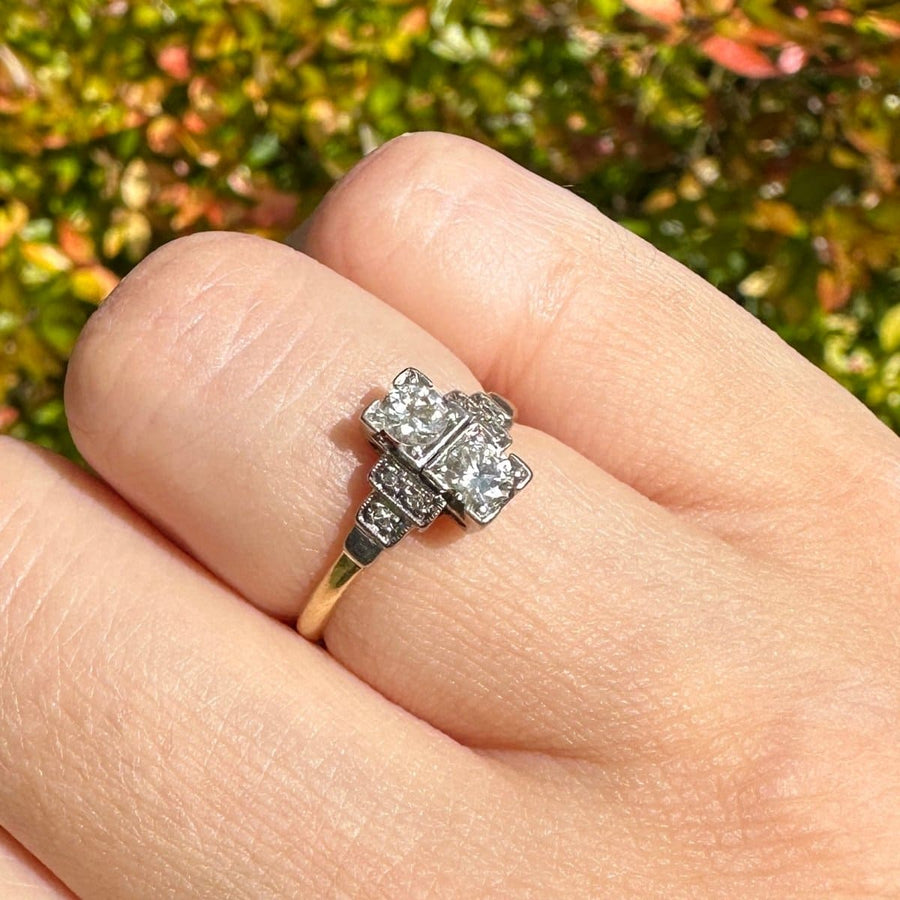 Art Deco 18ct gold and platinum two stone diamond ring with small diamonds on shoulders, showcasing geometric design.
