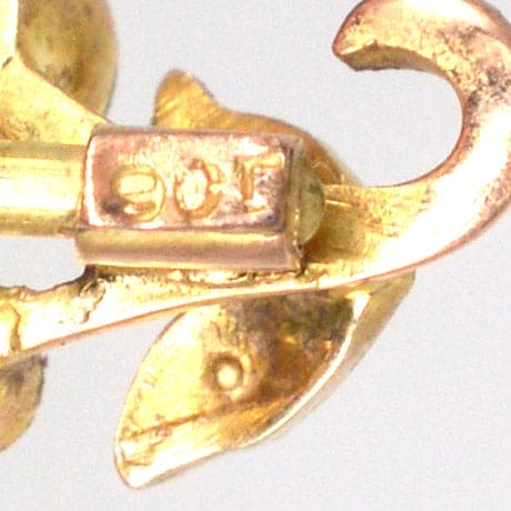 Close-up view of 9ct gold tie pin with floral design and hallmark, showcasing craftsmanship and elegance.