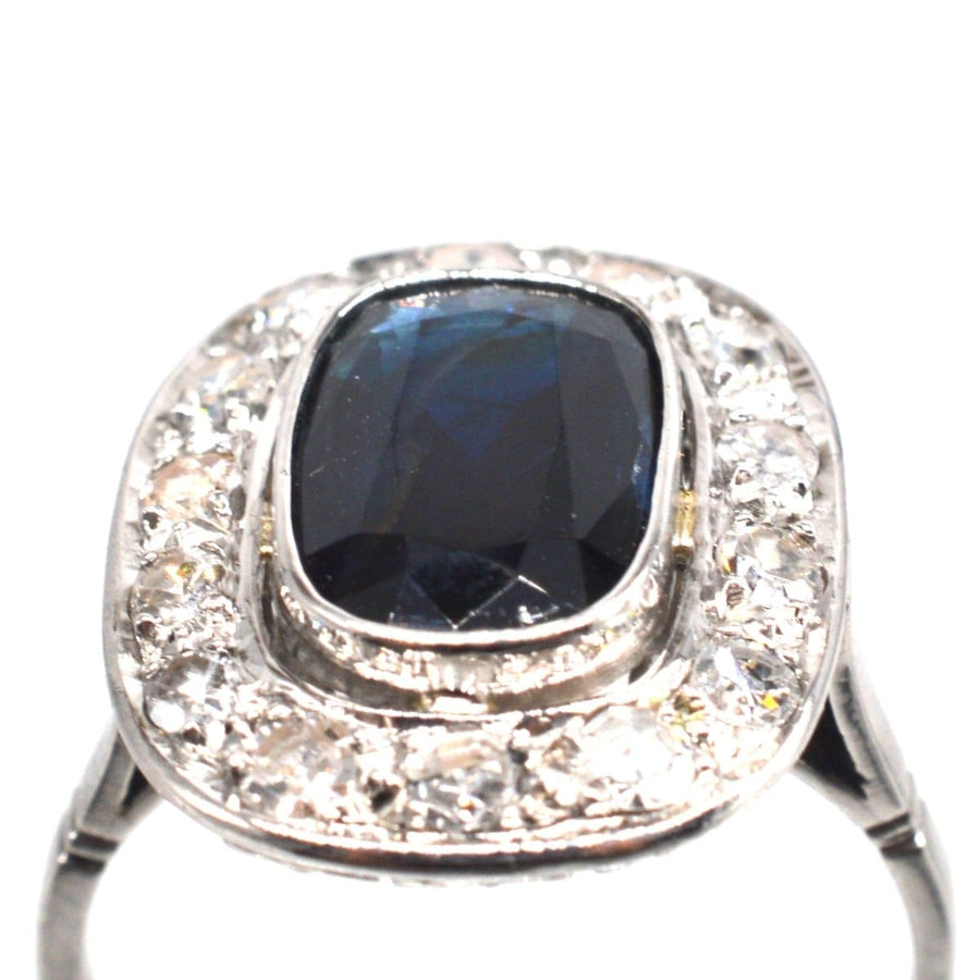 Art Deco platinum ring featuring a dark sapphire surrounded by shimmering diamonds, perfect for an engagement.
