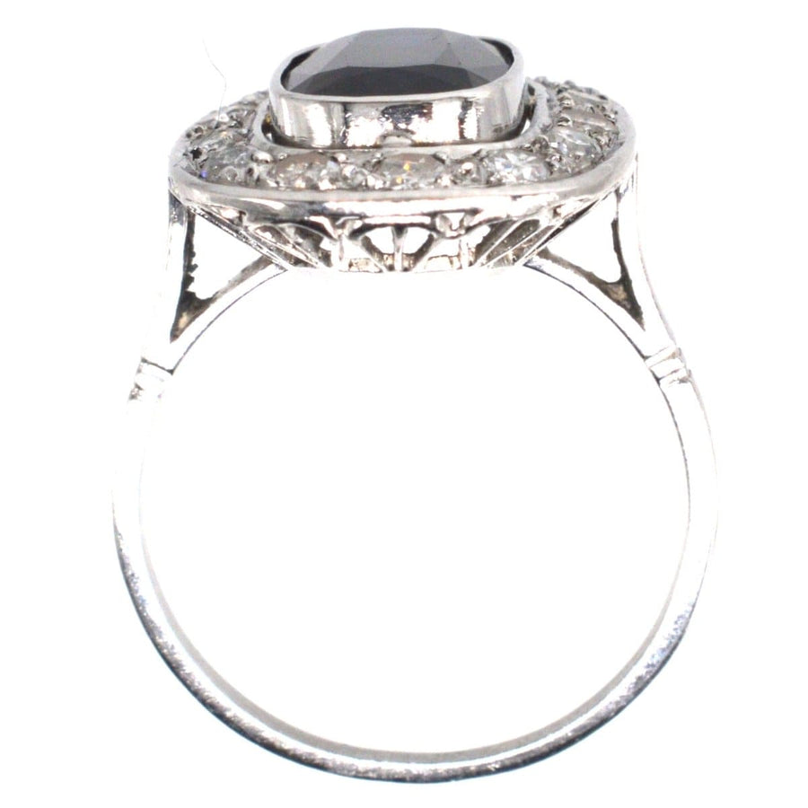 Art Deco French platinum ring with dark sapphire centerpiece and diamond cluster, perfect for engagement.
