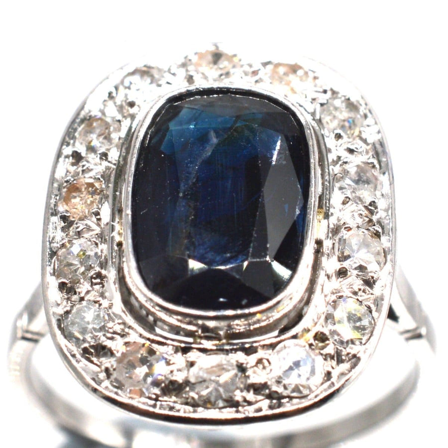 Art Deco platinum ring featuring a large dark blue sapphire surrounded by sparkling diamonds, ideal for engagements.
