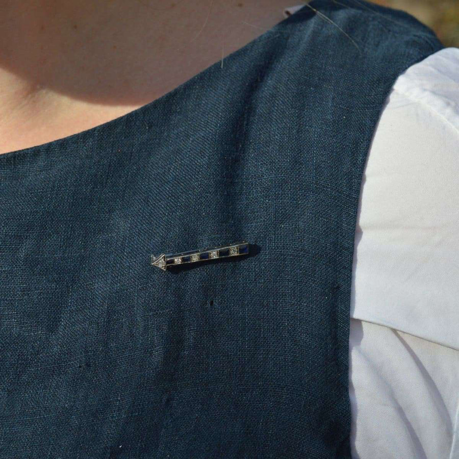 Art Deco French sapphire and diamond arrow brooch worn on lapel, showcasing its stylish design.