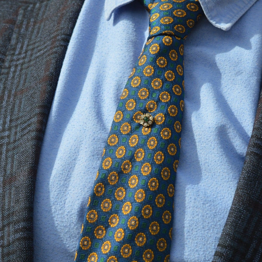 Stylish Art Deco green and white paste cluster tie pin on a colorful silk tie with a blue shirt and patterned blazer.