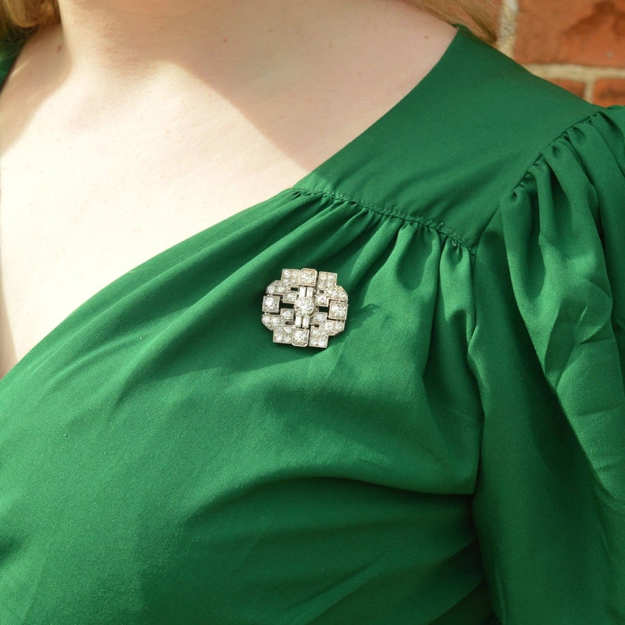 Art Deco platinum brooch with 7 carats of diamonds on a green dress, showcasing geometric design.
