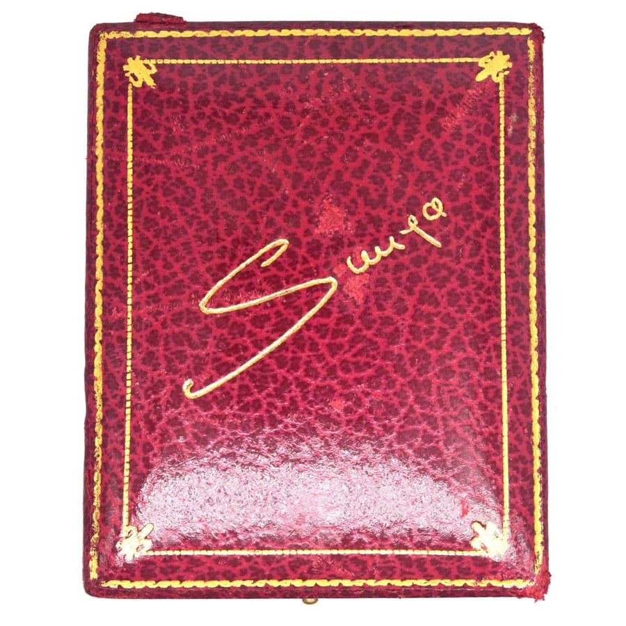 Vintage red leather case with gold detailing and signature, ideal for storing jewelry or accessories.