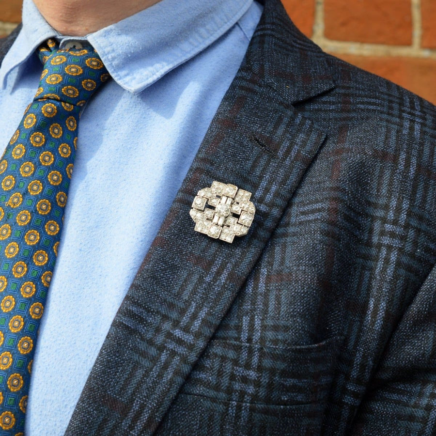Art Deco platinum 7 carat diamond brooch elegantly worn on a blazer lapel, showcasing geometric design and sparkle.