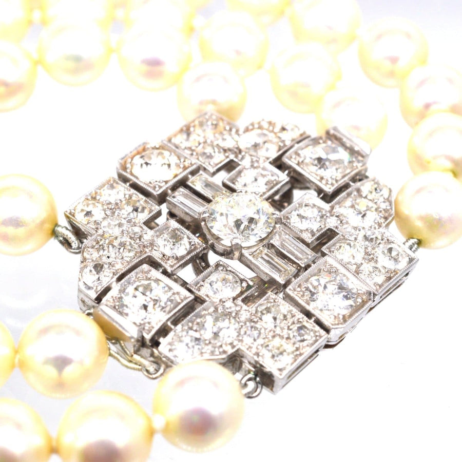 Art Deco platinum brooch with 7 carat diamonds and pearl necklace attachment, featuring bold geometric design.