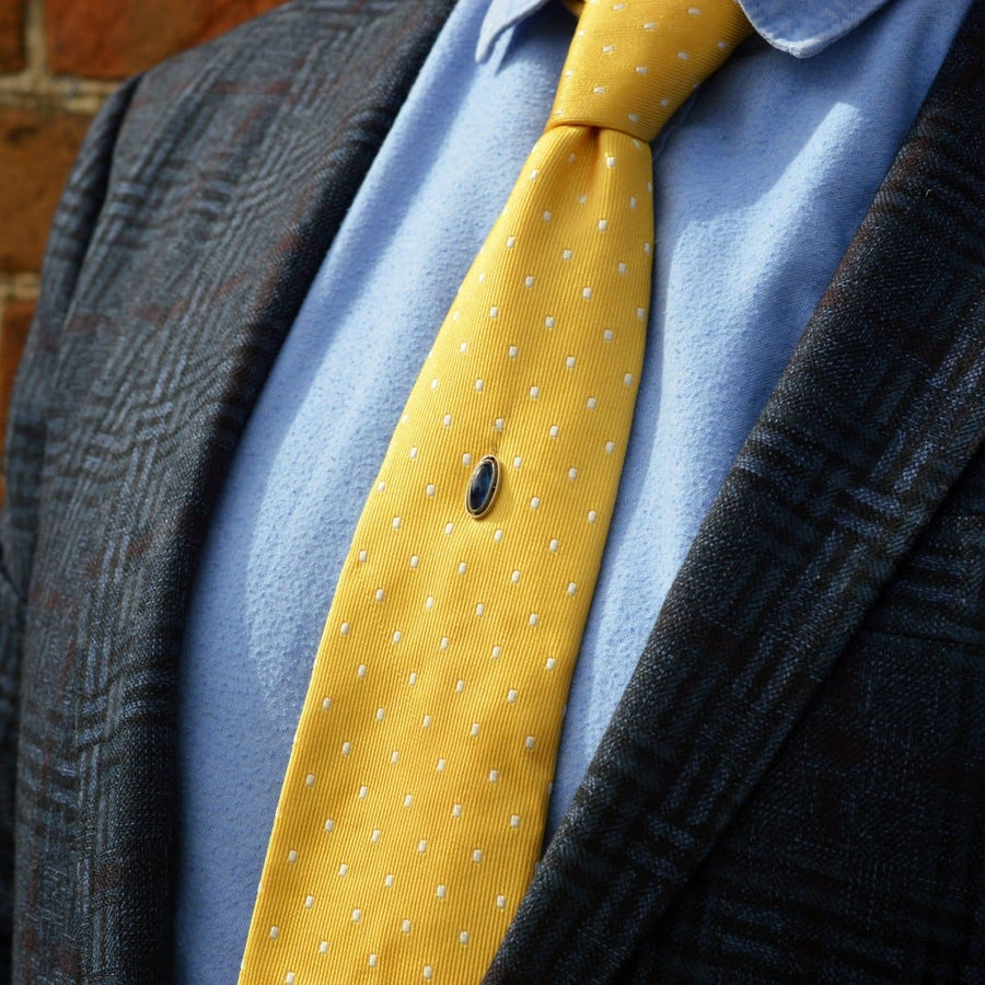 Art Deco platinum and sapphire tie pin showcased on a stylish yellow polka dot tie and jacket.