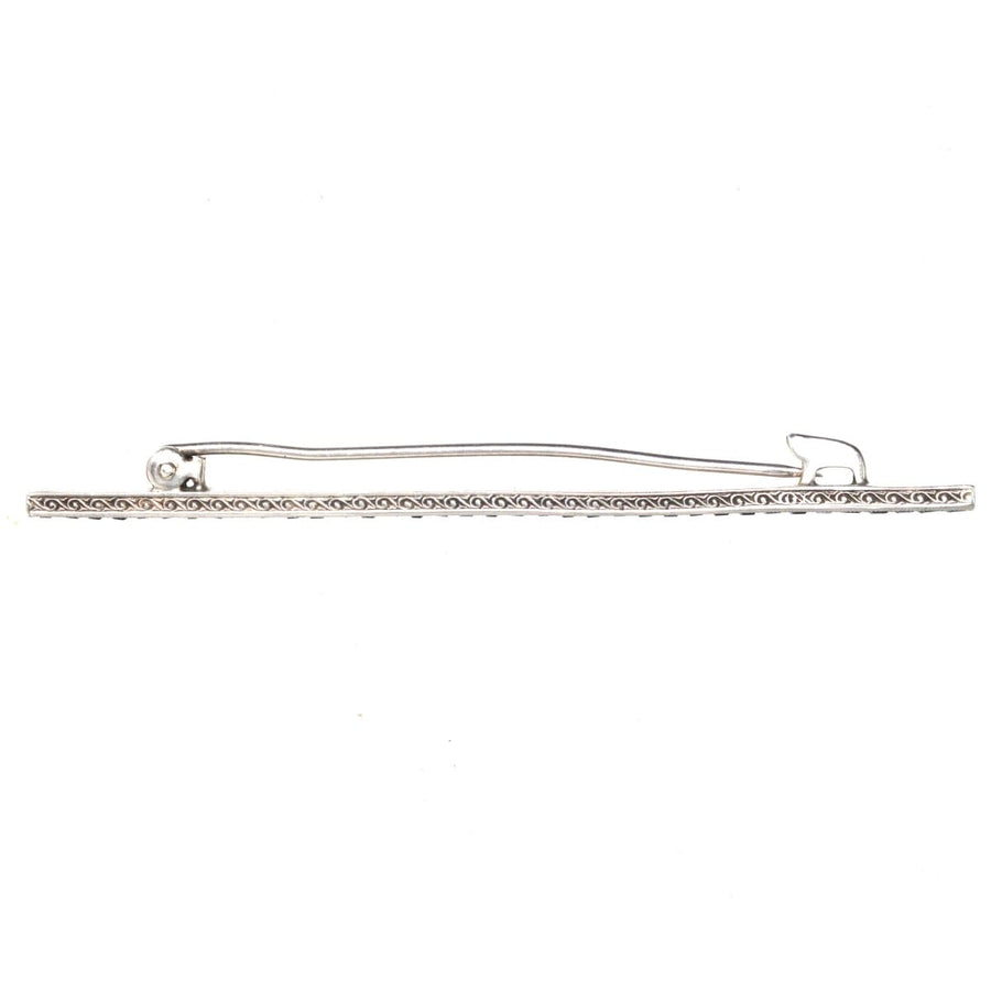 Art Deco silver bar brooch featuring intricate detailing and blue paste stones resembling sapphires.