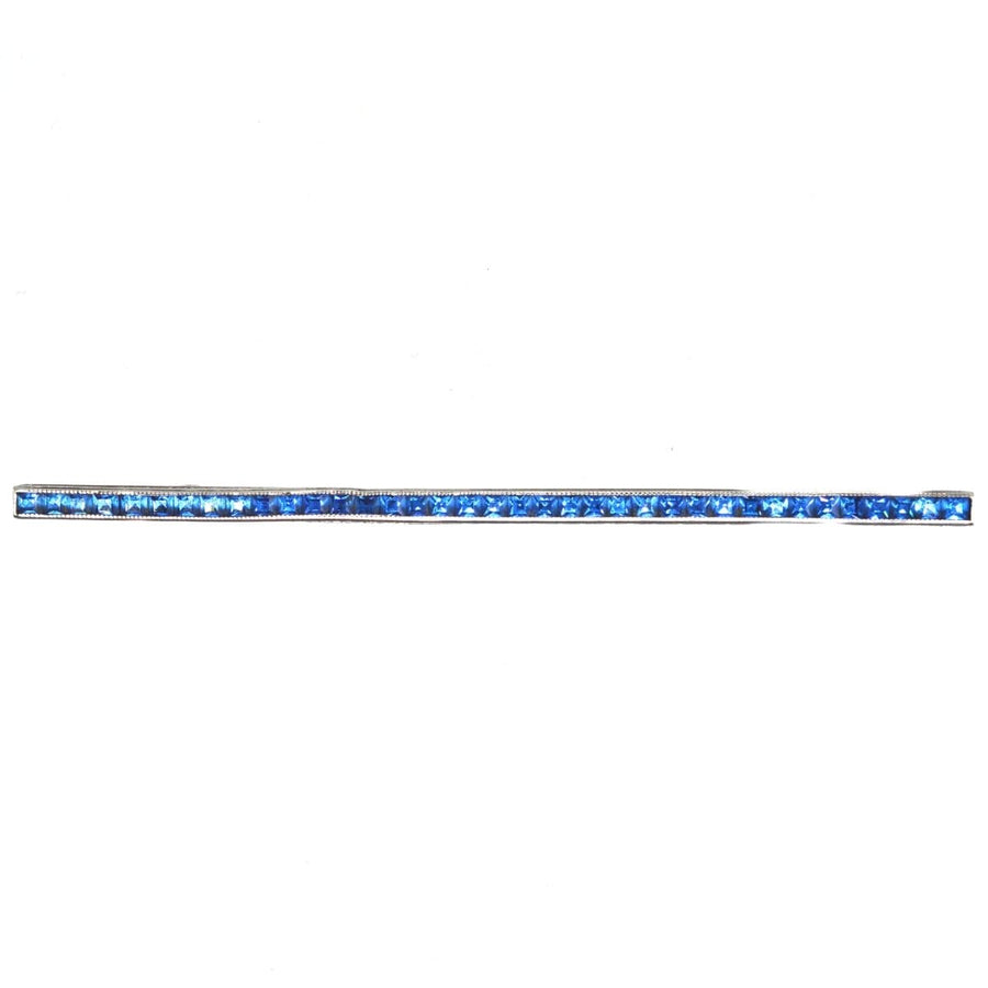 Art Deco silver bar brooch with blue paste stones resembling sapphires, featuring intricate deco detailing.