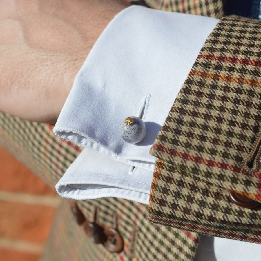Close-up of a man's cuff showcasing Art Deco speckled glass bead cufflinks with a gold-tone flower detail.