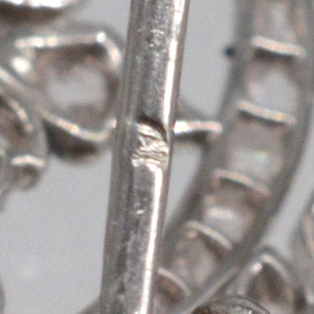 Close-up of ornate floral motifs on a Belle Epoque 18ct white gold diamond brooch and pendant.