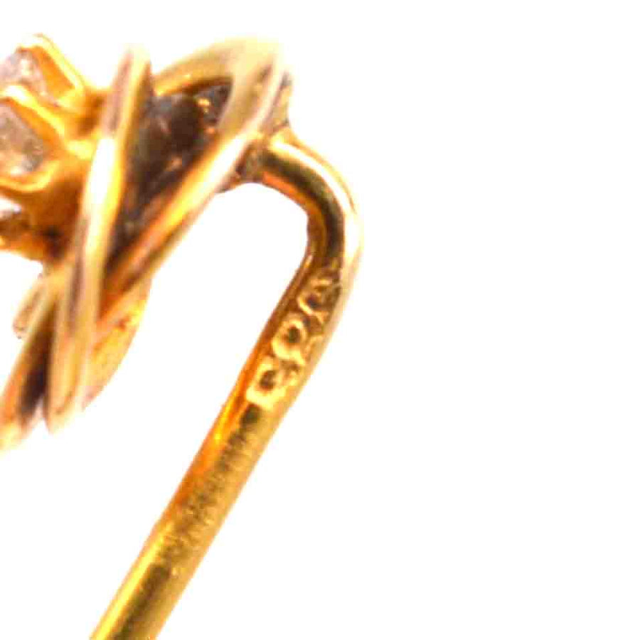 Close-up of an early 20th century 14ct gold knot tie pin with a diamond, showcasing intricate design.