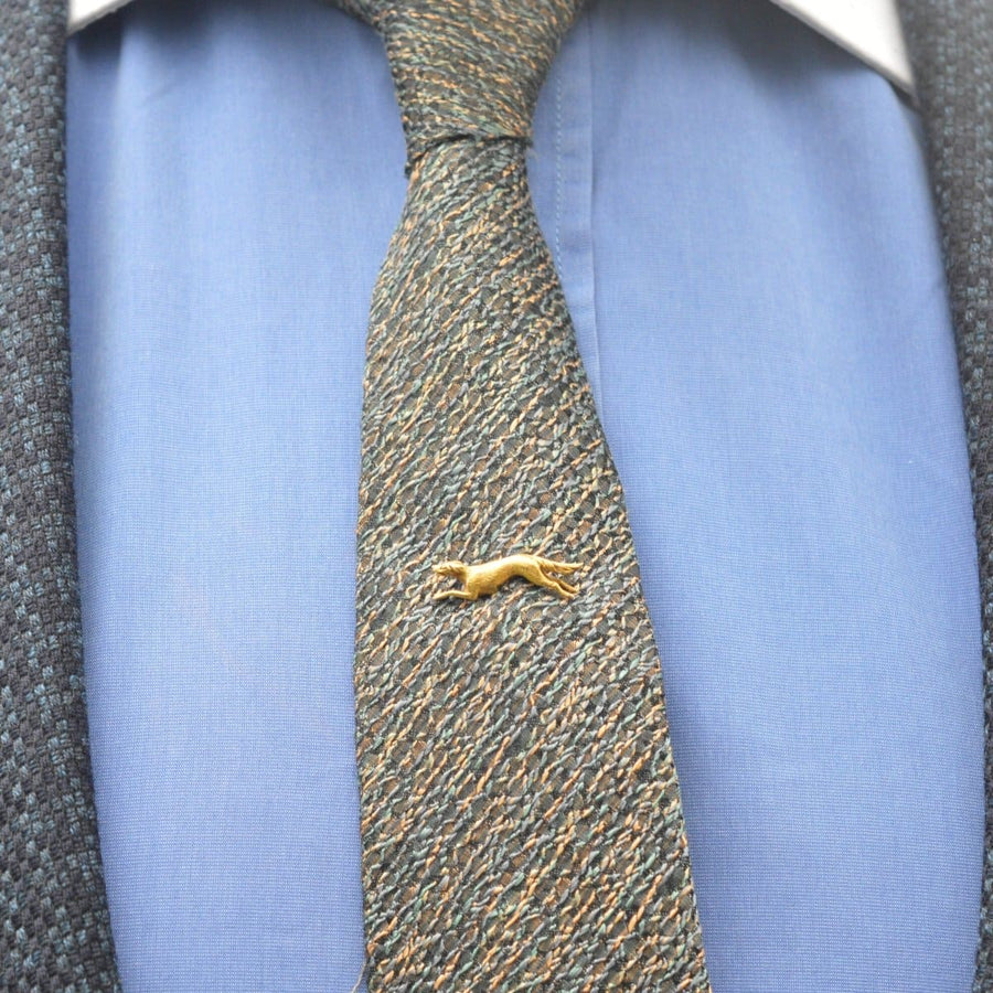 Early 20th century gold tie pin featuring a running canine dog on a textured tie, showcasing fine craftsmanship.