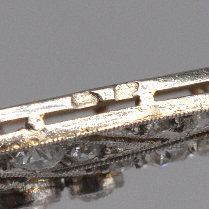 Close-up of early 20th century French diamond brooch showcasing intricate platinum and gold craftsmanship.