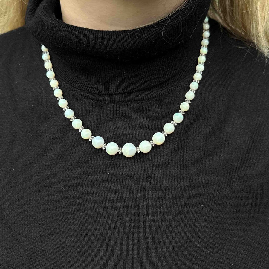 Early 20th century graduated opal bead necklace worn on a black turtleneck, showcasing its luminous quality.