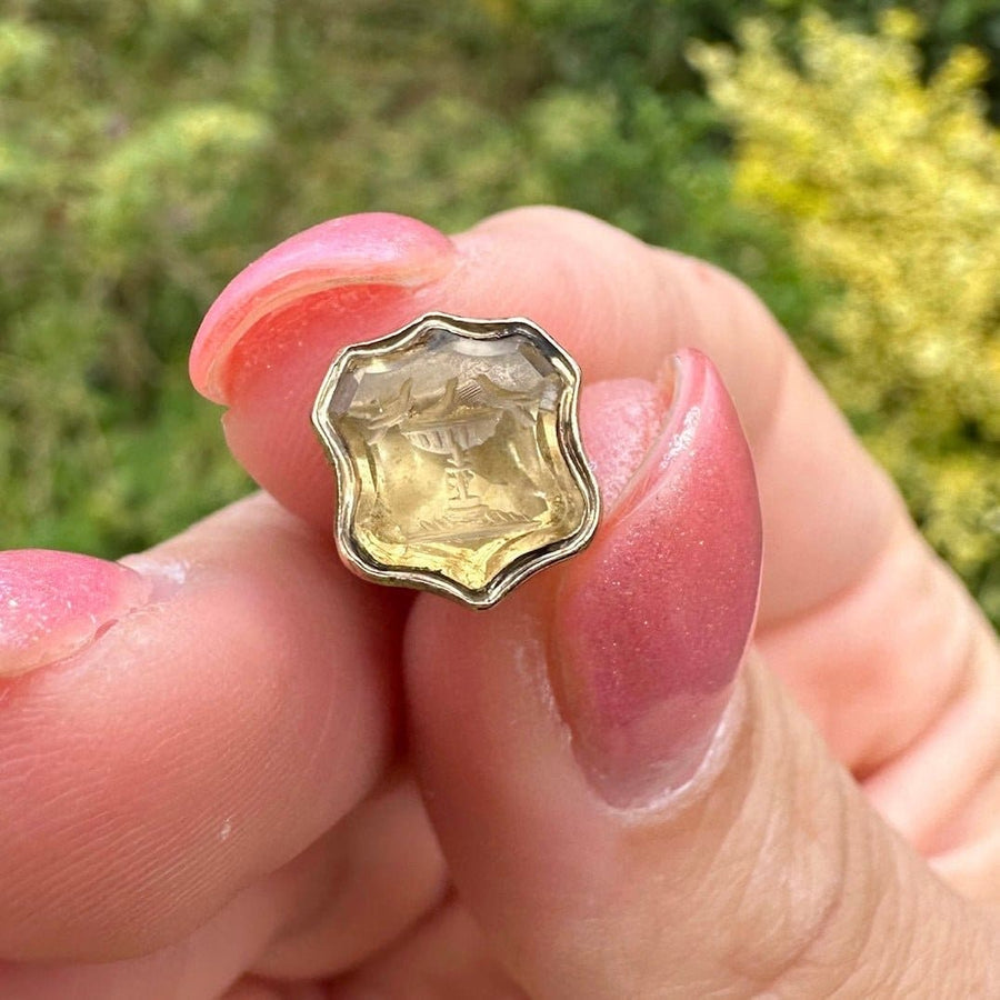 Early Victorian gold seal with citrine intaglio depicting the Doves of Pliny, held in hand outdoors.