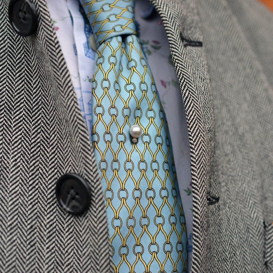 Elegant Edwardian 14ct gold stickpin with natural pearl and diamond, accentuating a stylish blue patterned silk tie.