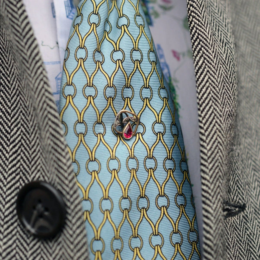 Edwardian 14ct gold tie pin with synthetic red spinel, set on a patterned blue tie.