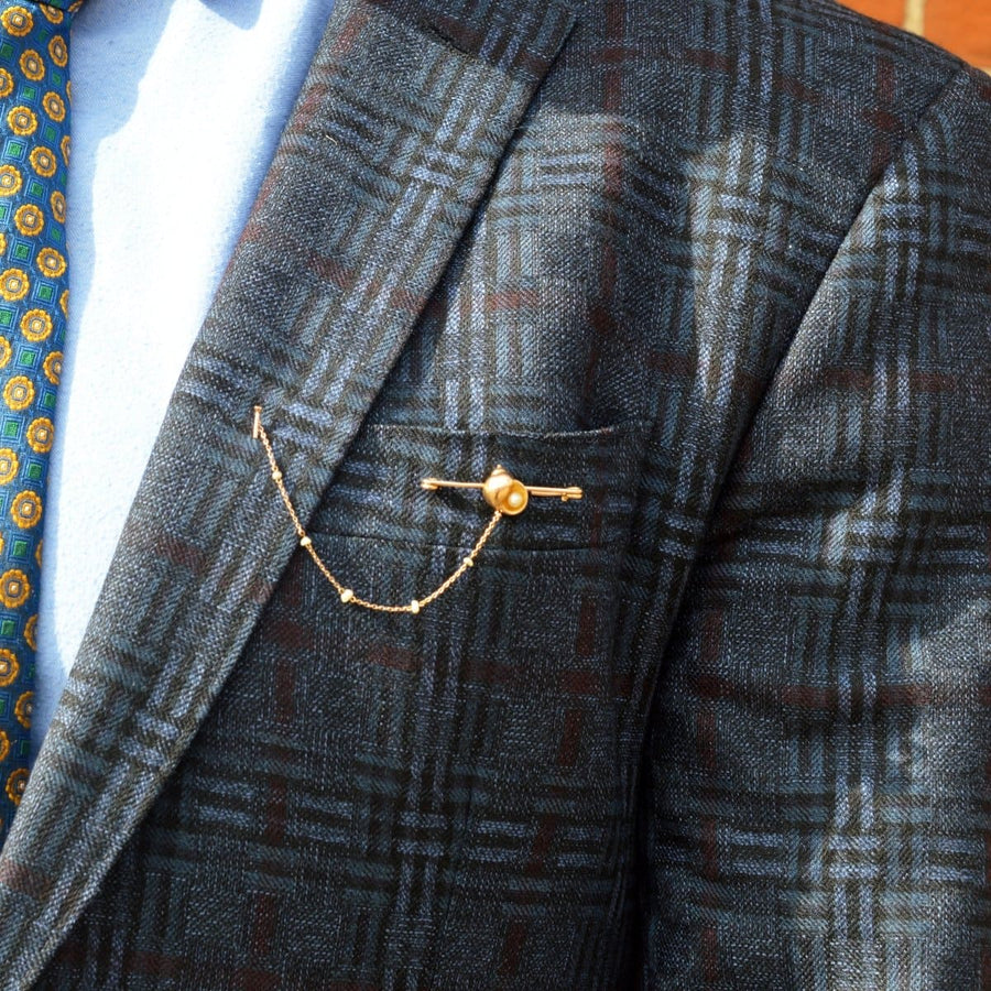 Elegant Edwardian 15ct gold brooch featuring seashell and pearl on stylish suit jacket.