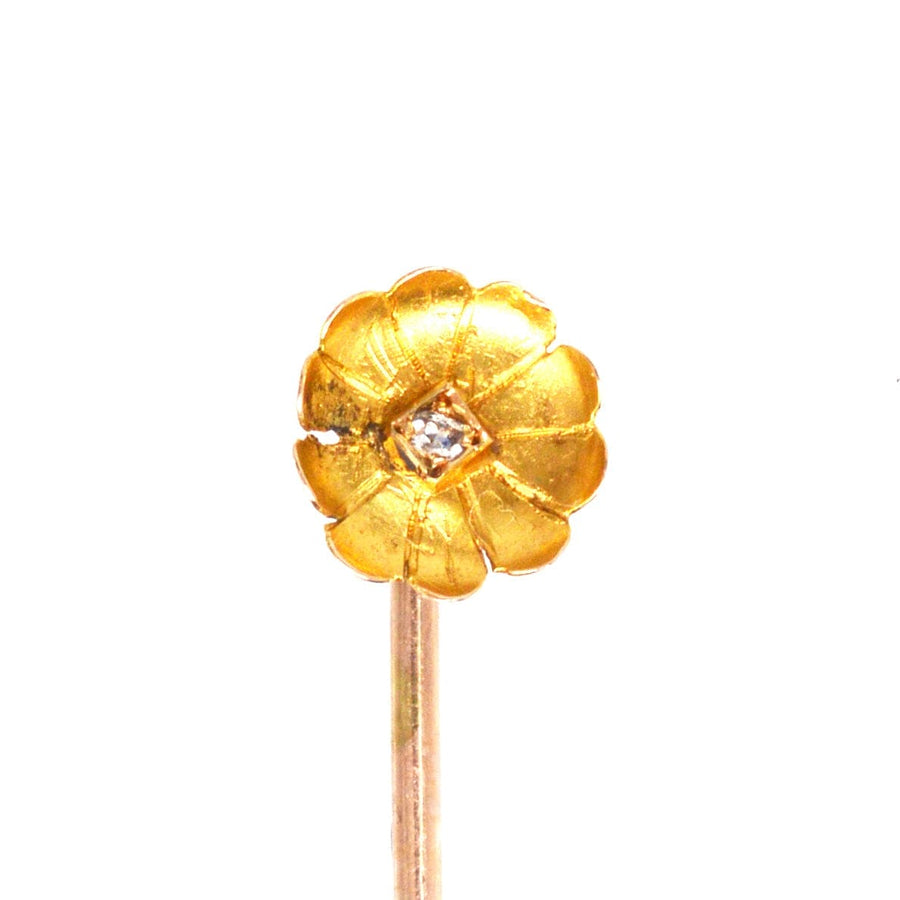 Elegant Edwardian 15ct gold flower tie pin with a diamond at the center and curled petal design.