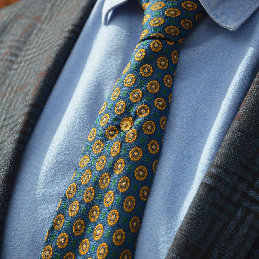 Elegant Edwardian 15ct gold flower tie pin with diamond, enhancing a patterned tie and shirt.