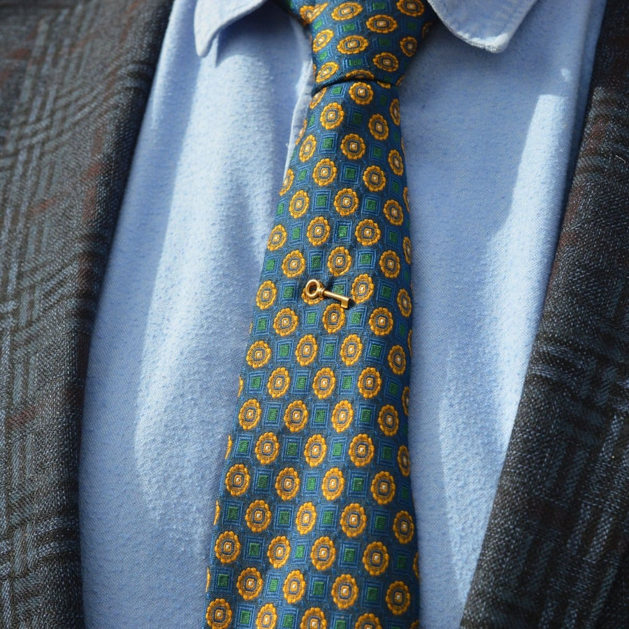 Edwardian 15ct gold key tie pin on a patterned tie, symbolizing love and success.