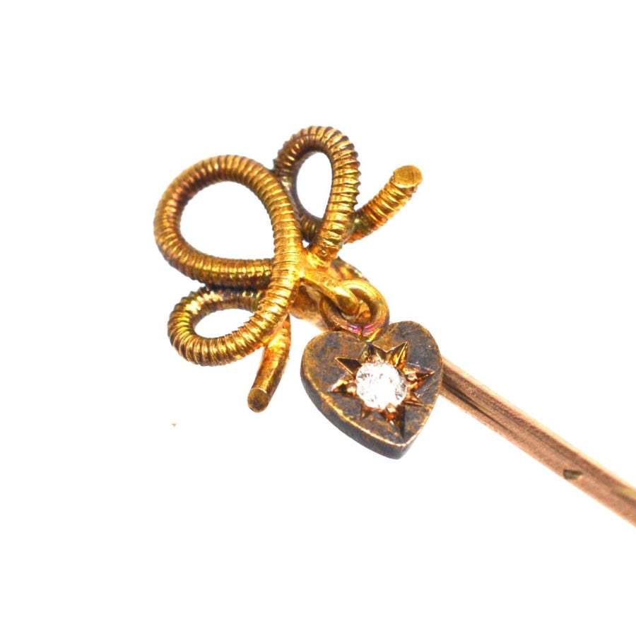 Edwardian 15ct gold knot tie pin with dangling diamond heart, symbolizing timeless love and romance.