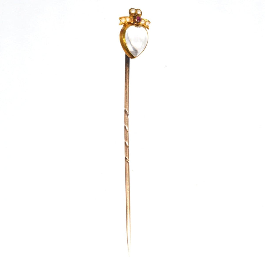 Edwardian 15ct gold heart pin featuring a moonstone, ruby, and seed pearl bow tie design for love and good luck.