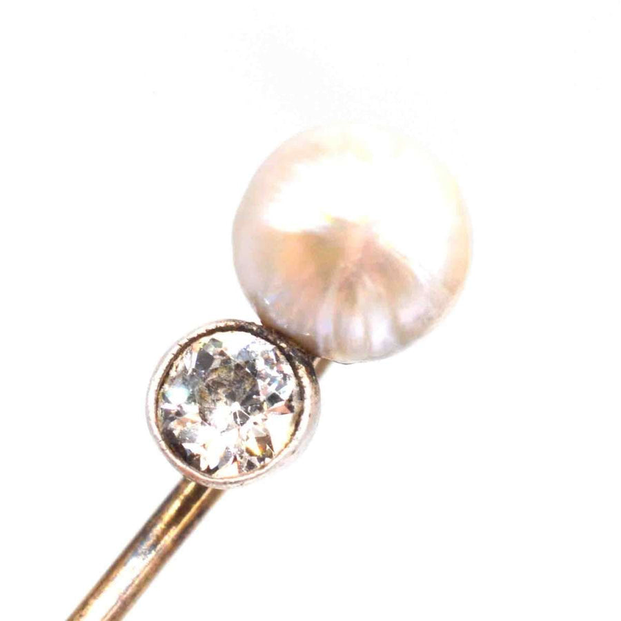 Edwardian 15ct gold pin featuring a natural pearl and a brilliant half-carat diamond, symbolizing elegance and refinement.