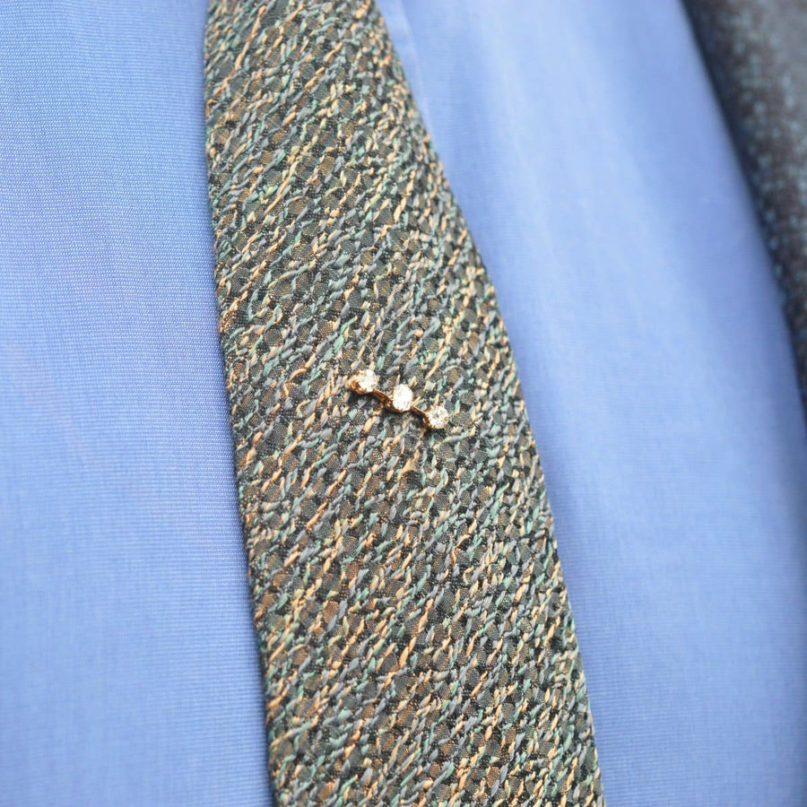 Edwardian 15ct gold three stone diamond tie pin on a textured tie, adding elegance to a formal outfit.