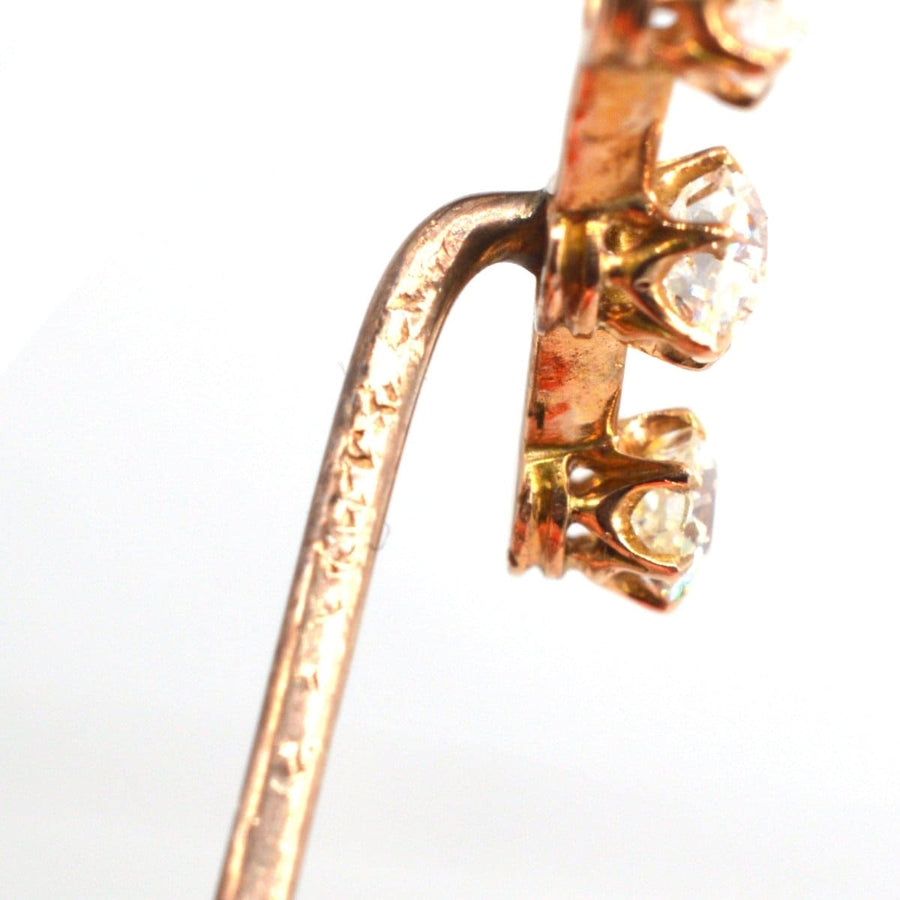 Close-up of Edwardian 15ct gold three stone diamond tie pin showcasing old cut diamonds and elegant design.