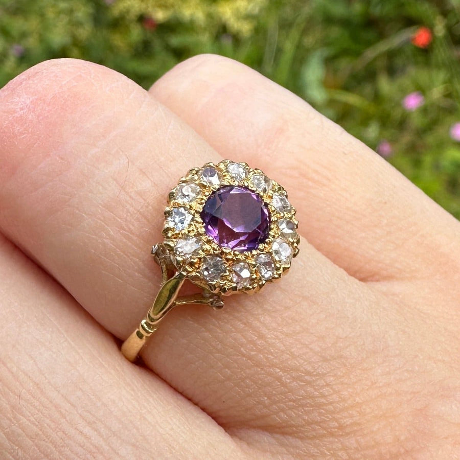 Edwardian 18ct gold amethyst and diamond cluster ring showcased on a hand outdoors.