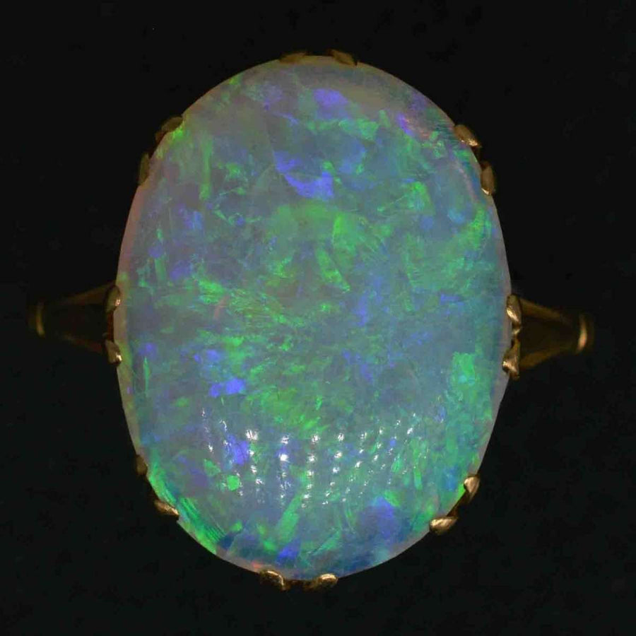 Large Edwardian 18ct gold opal ring showcasing vivid green and blue flashes in an oval opal setting.
