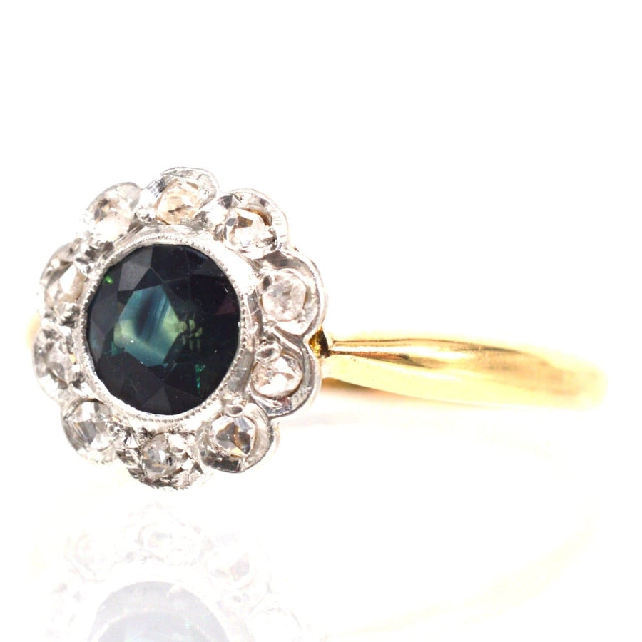 Edwardian 18ct gold cluster ring featuring a teal sapphire surrounded by sparkling diamonds.