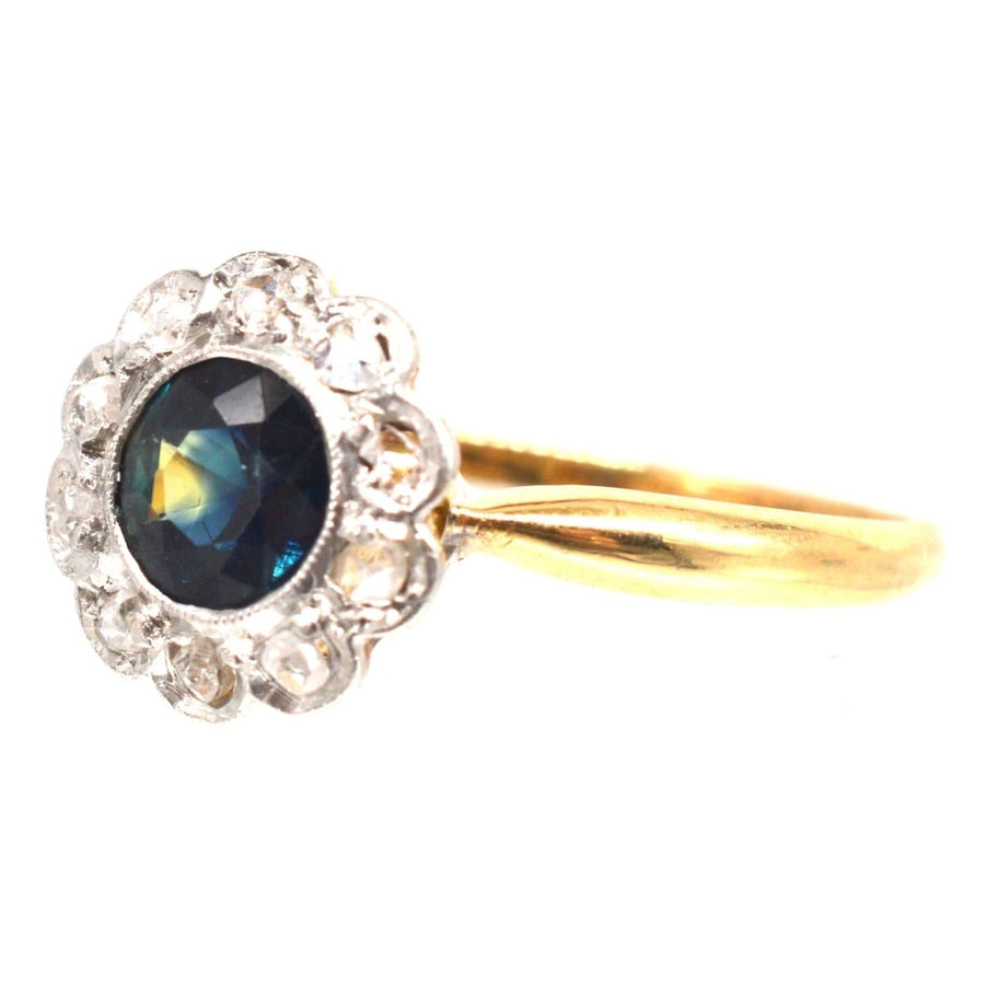 Edwardian 18ct gold cluster ring featuring a teal sapphire surrounded by sparkling diamonds.